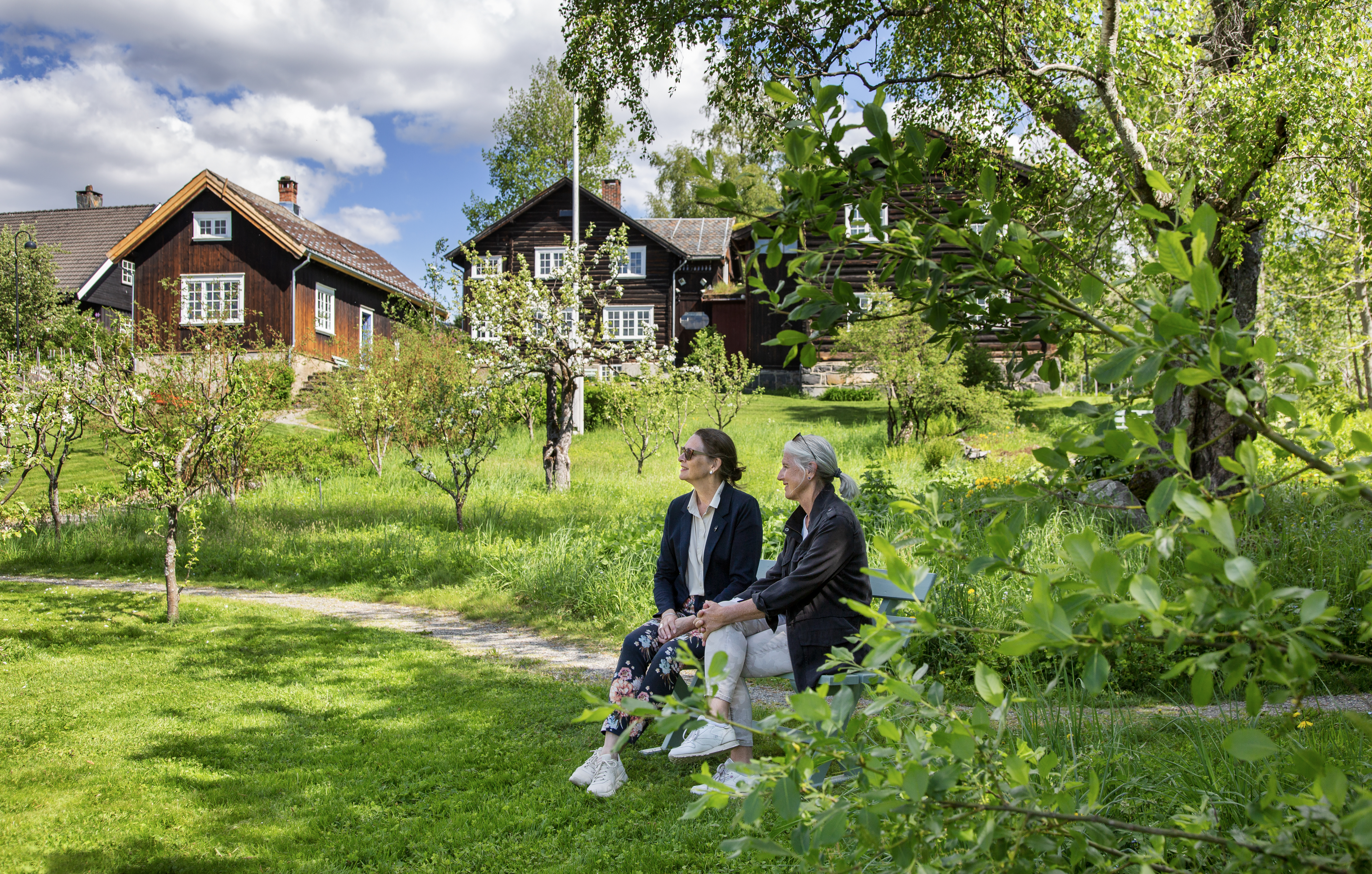 Gjester sitter på benk i hagen på Bjerkebæk